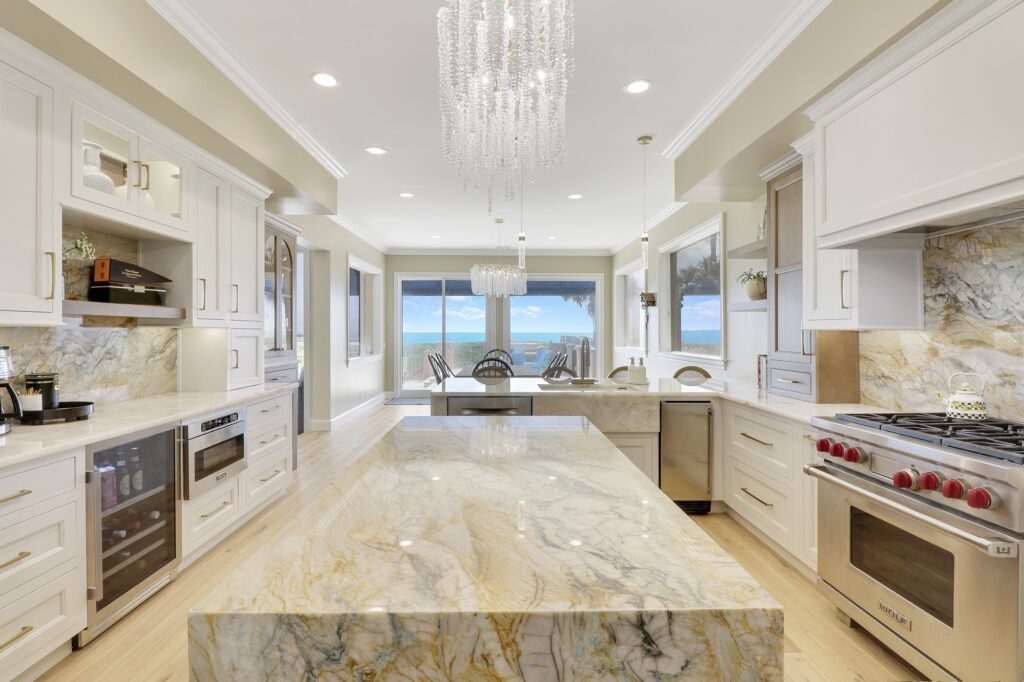 A kitchen with white cabinets , stainless steel appliances , granite counter tops and a large island.
