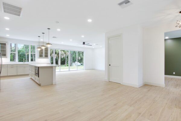 A large empty room with hardwood floors and a kitchen.