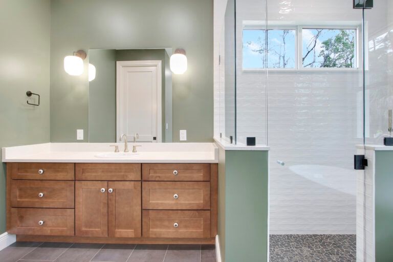 A bathroom with two sinks , a shower and a window.