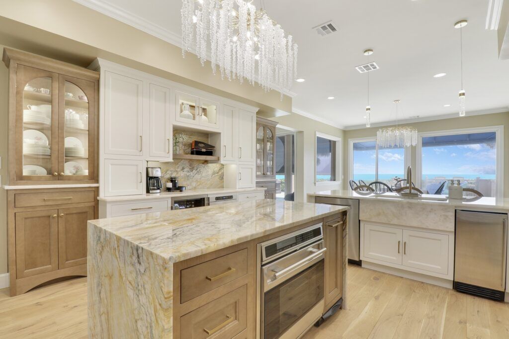 A kitchen with a large island , stainless steel appliances , granite counter tops and a chandelier.