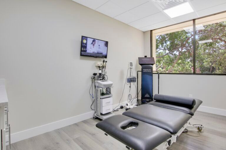 A room with a massage table and a television on the wall.