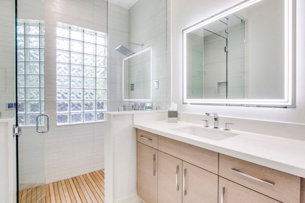 A bathroom with a sink , mirror and walk in shower.