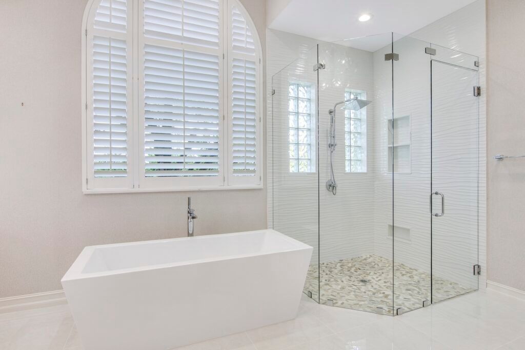 A bathroom with a tub , shower , and window.