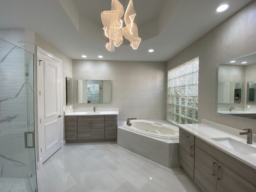 A bathroom with a tub , sinks , mirrors and a chandelier.