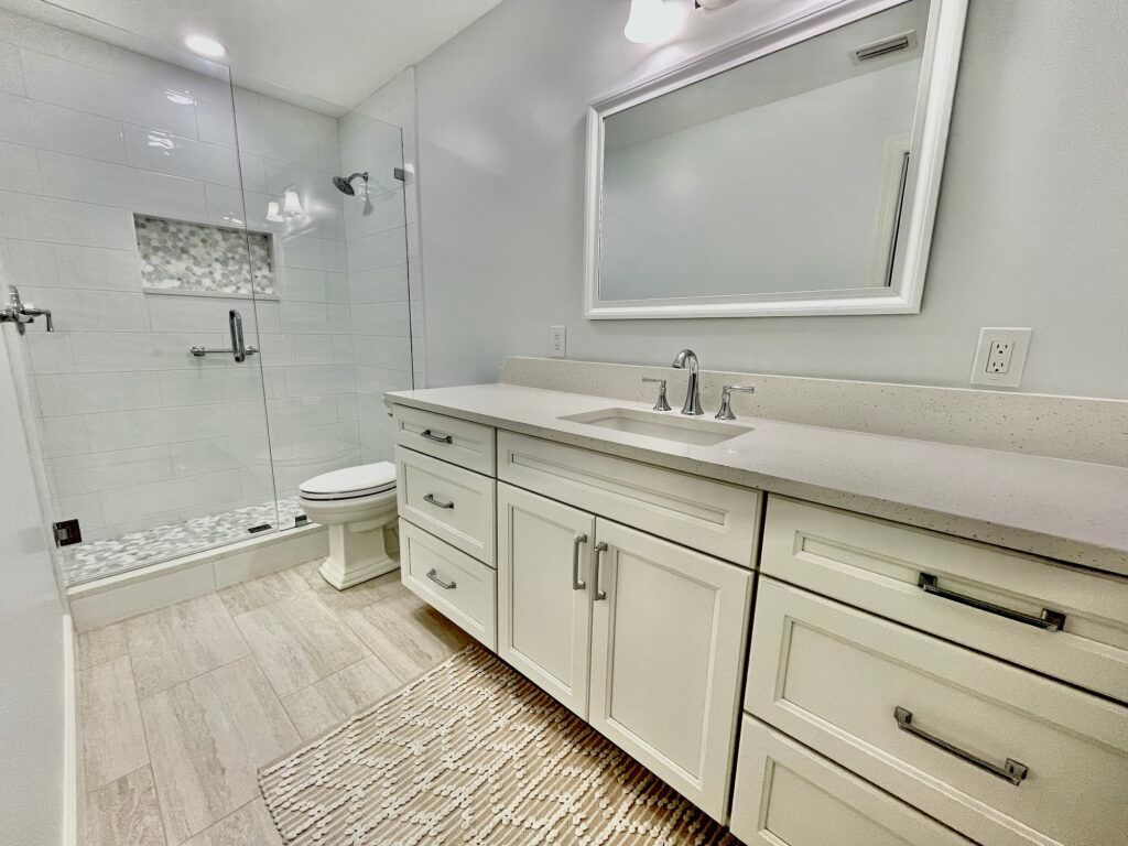 A bathroom with a sink , toilet , shower and mirror.
