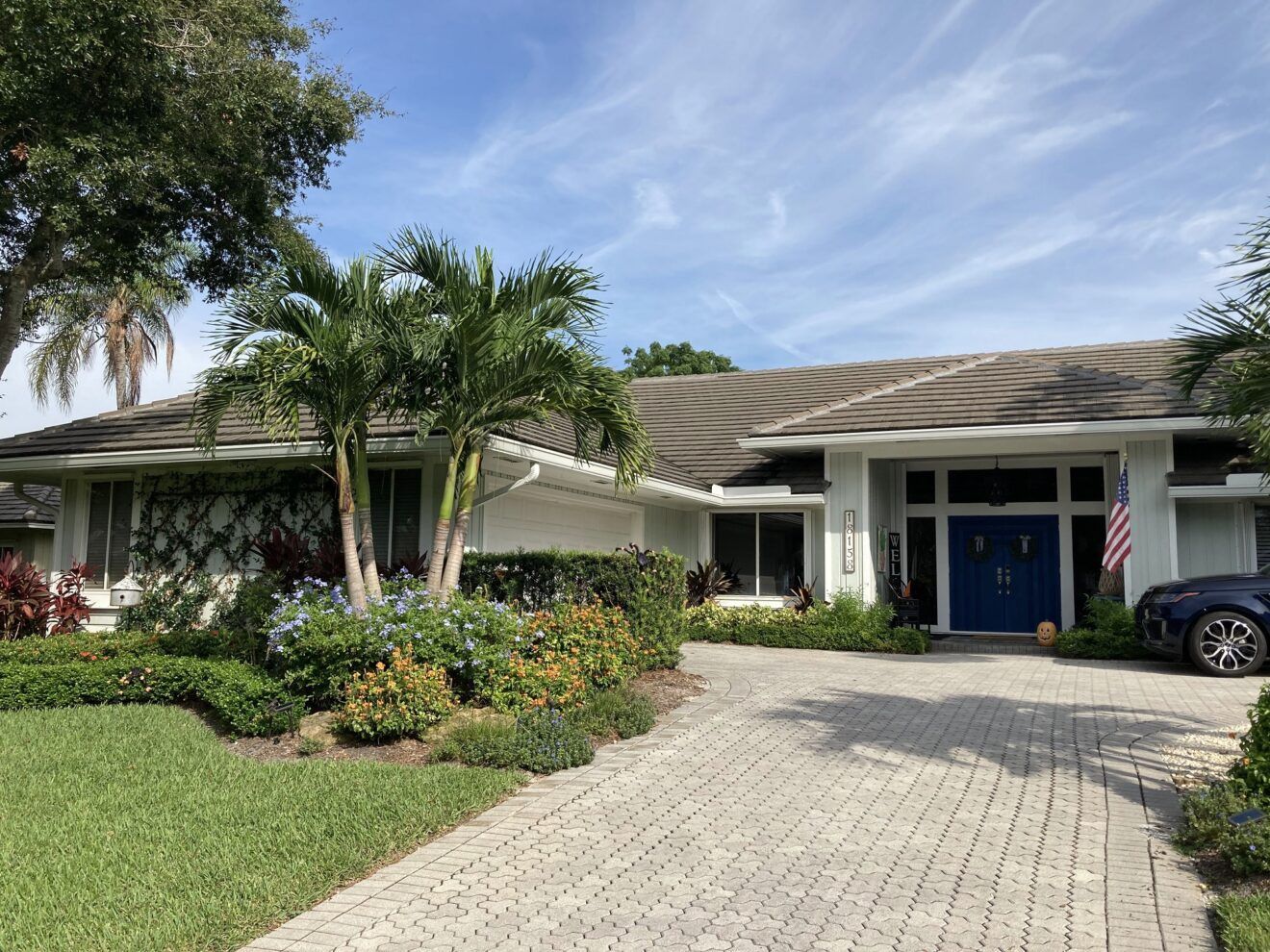 A large white house with a blue car parked in front of it.