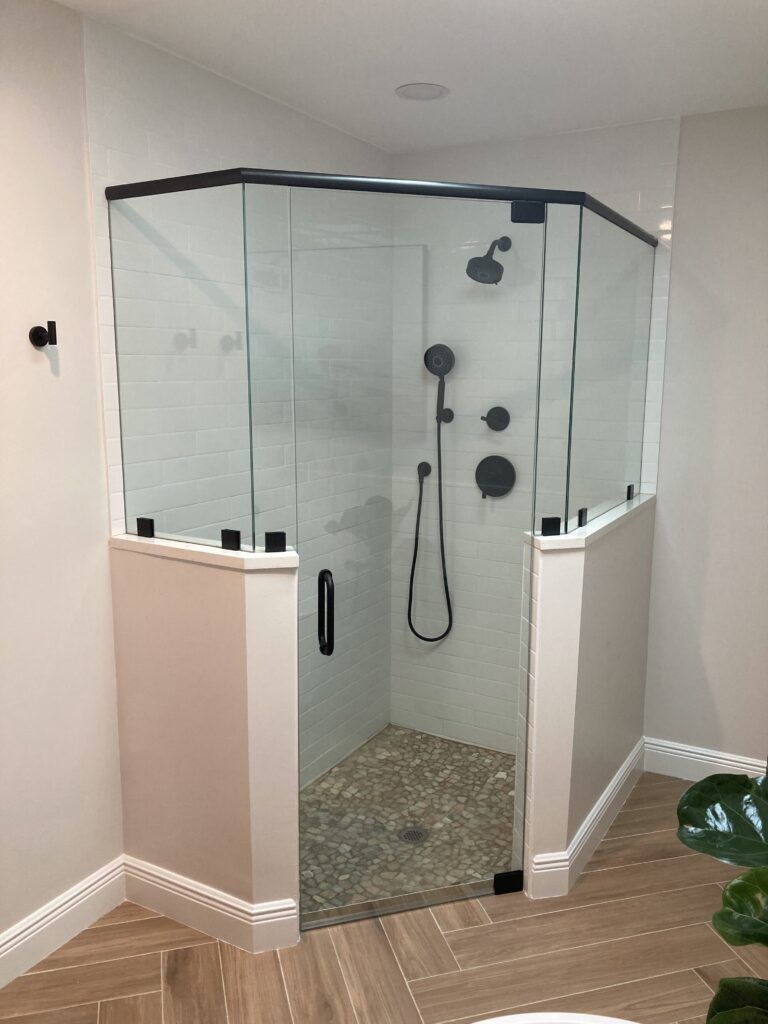 A bathroom with a walk in shower with a glass door.