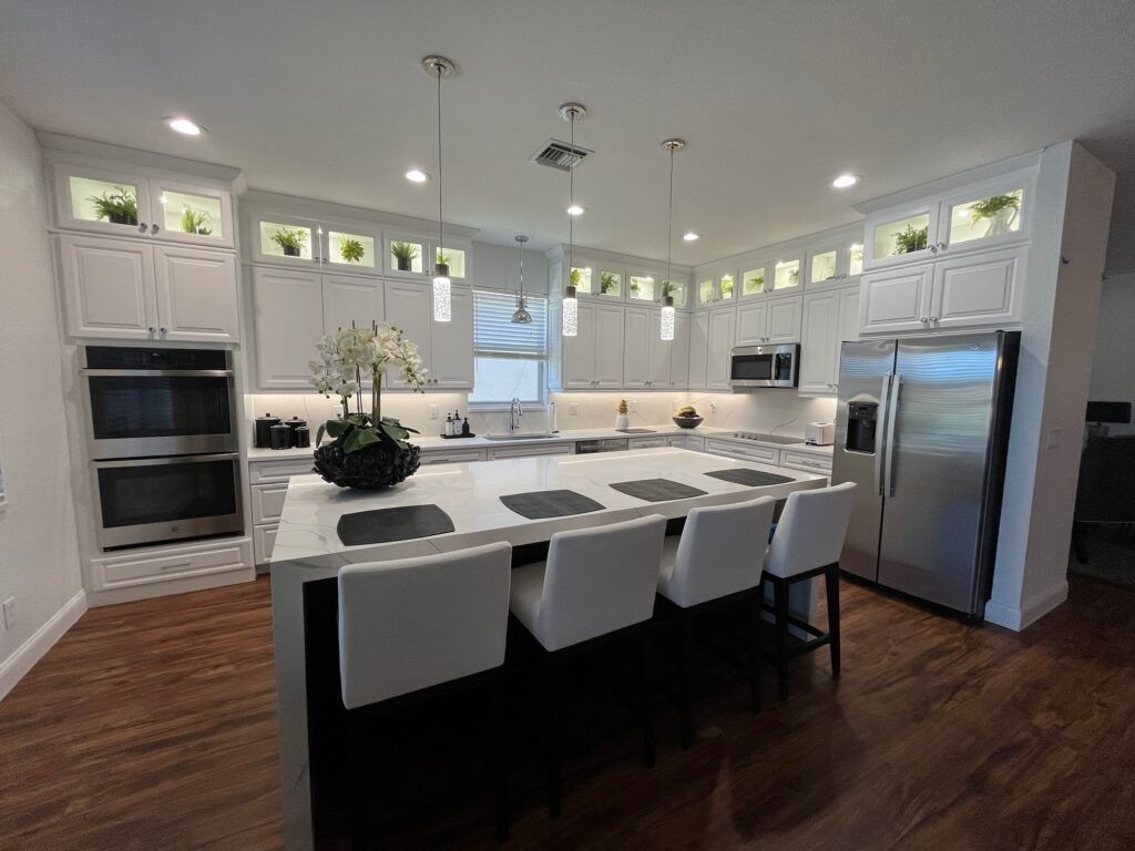 A kitchen with white cabinets and stainless steel appliances and a large island.