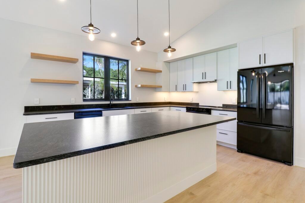 A kitchen with a large island and a black refrigerator.