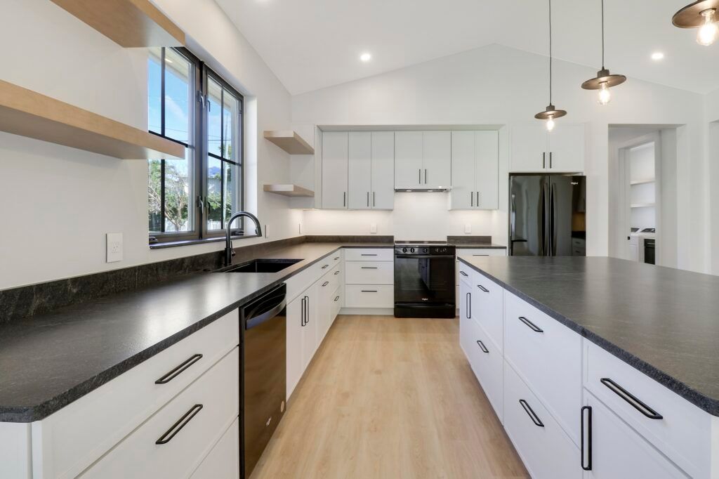 A kitchen with white cabinets and black counter tops