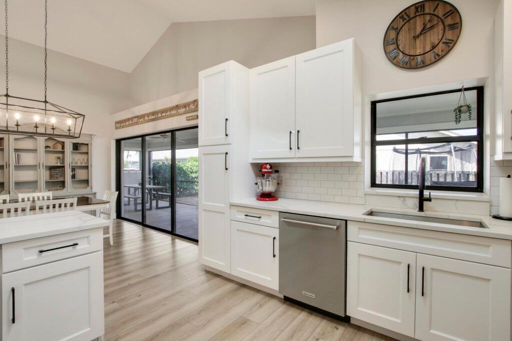 A kitchen with white cabinets and a clock on the wall.