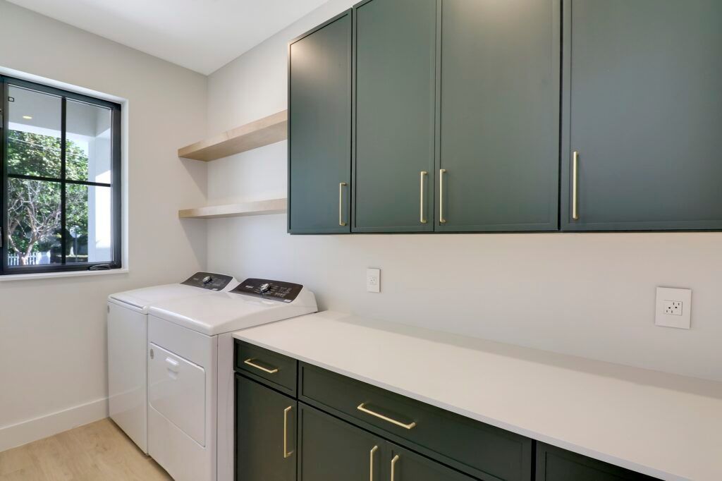 A laundry room with a washer and dryer and green cabinets.