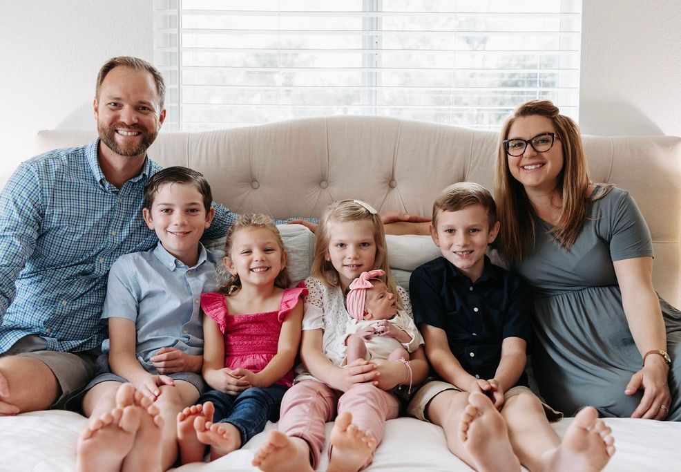 A family is posing for a picture while sitting on a bed.