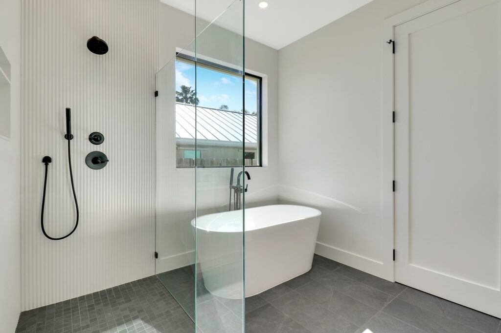 A bathroom with a tub , shower , and window.