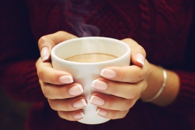 A woman is holding a cup of coffee in her hands.