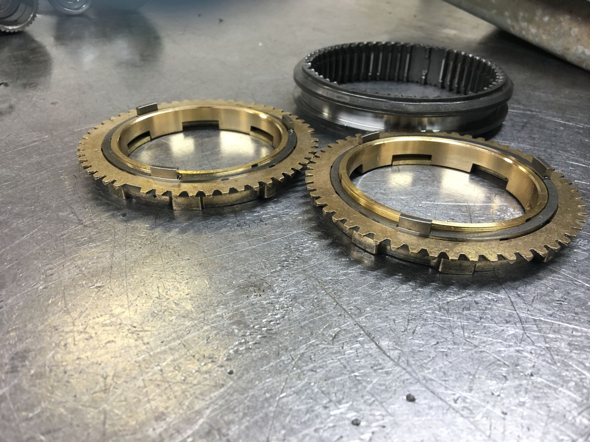 Two brass gears are sitting on a metal surface.