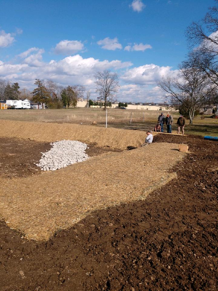 A group of people are working on a dirt field.