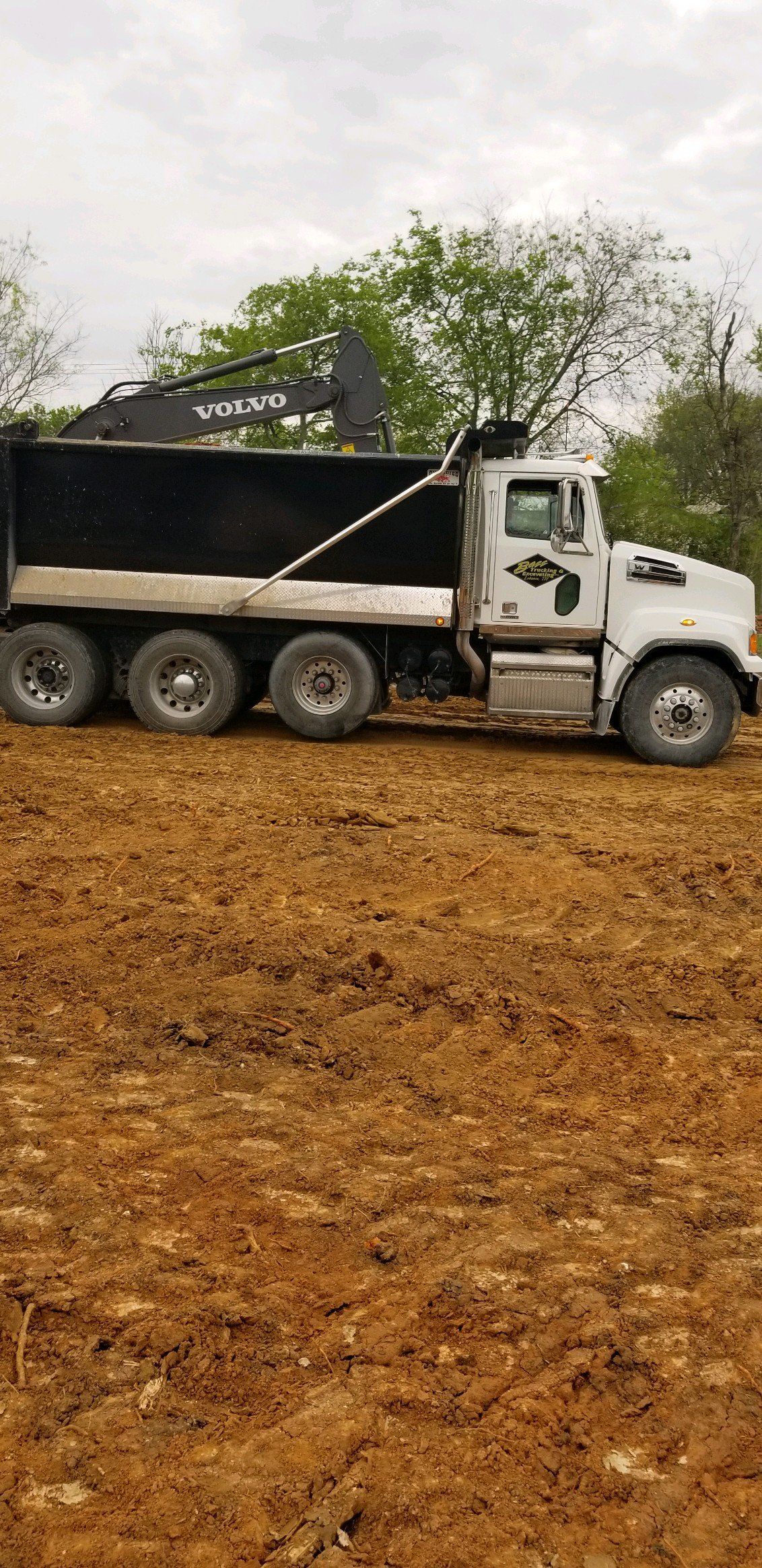 A dump truck is parked in a dirt field.
