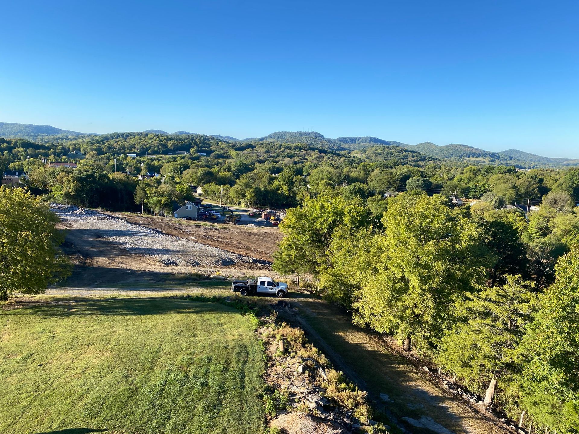 An aerial view of a field with trees and mountains in the background.