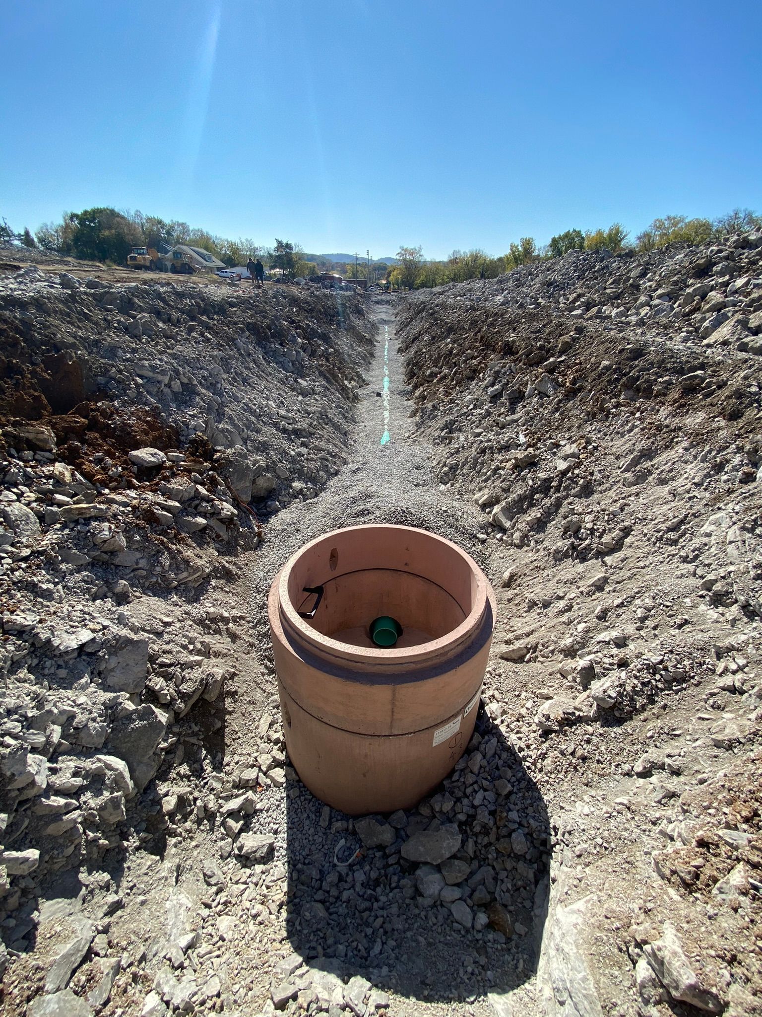 A barrel is sitting in the middle of a dirt field.