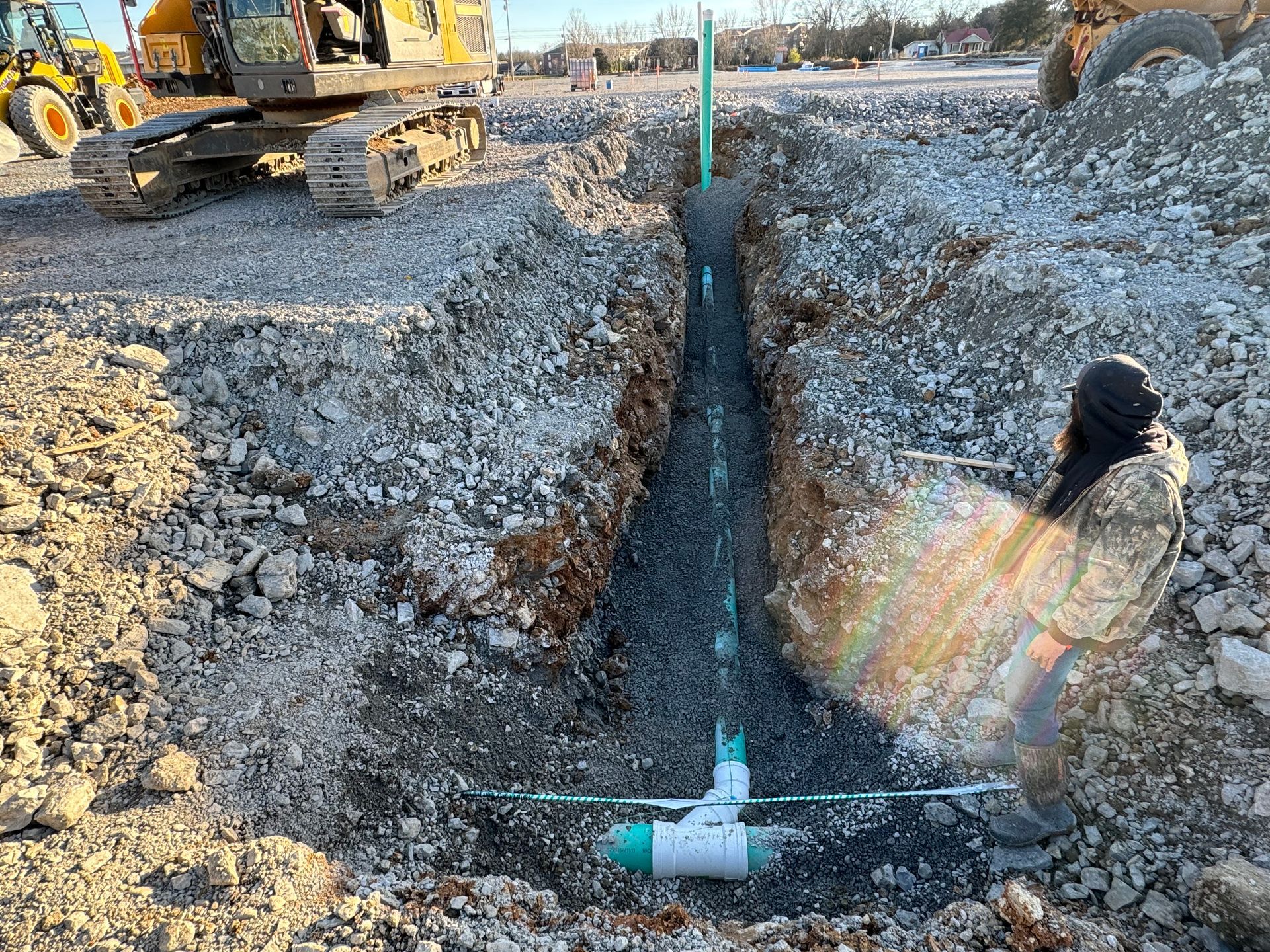 A man is digging a hole in the ground to install a pipe.