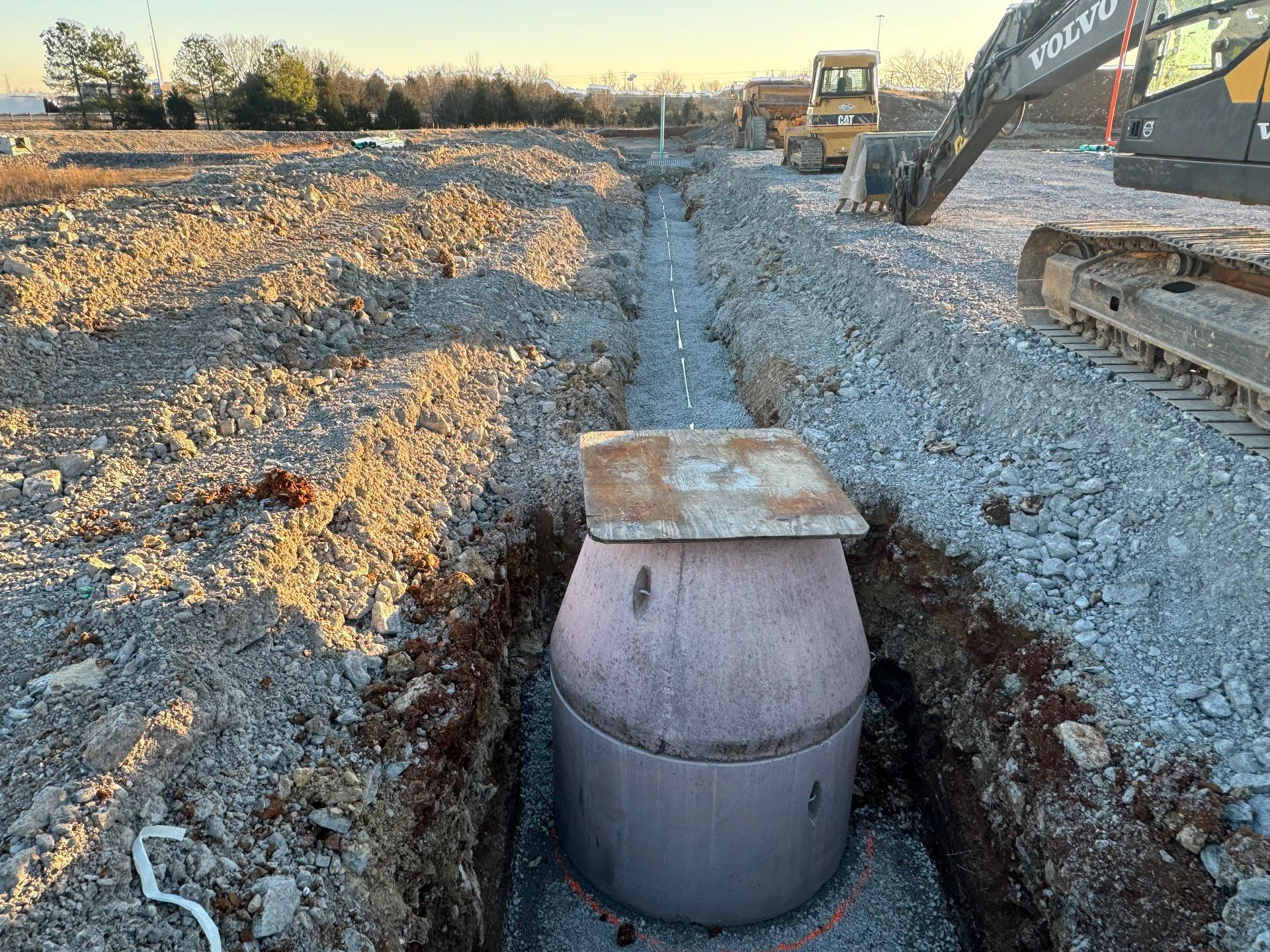 A large concrete cylinder is sitting in the middle of a dirt field.