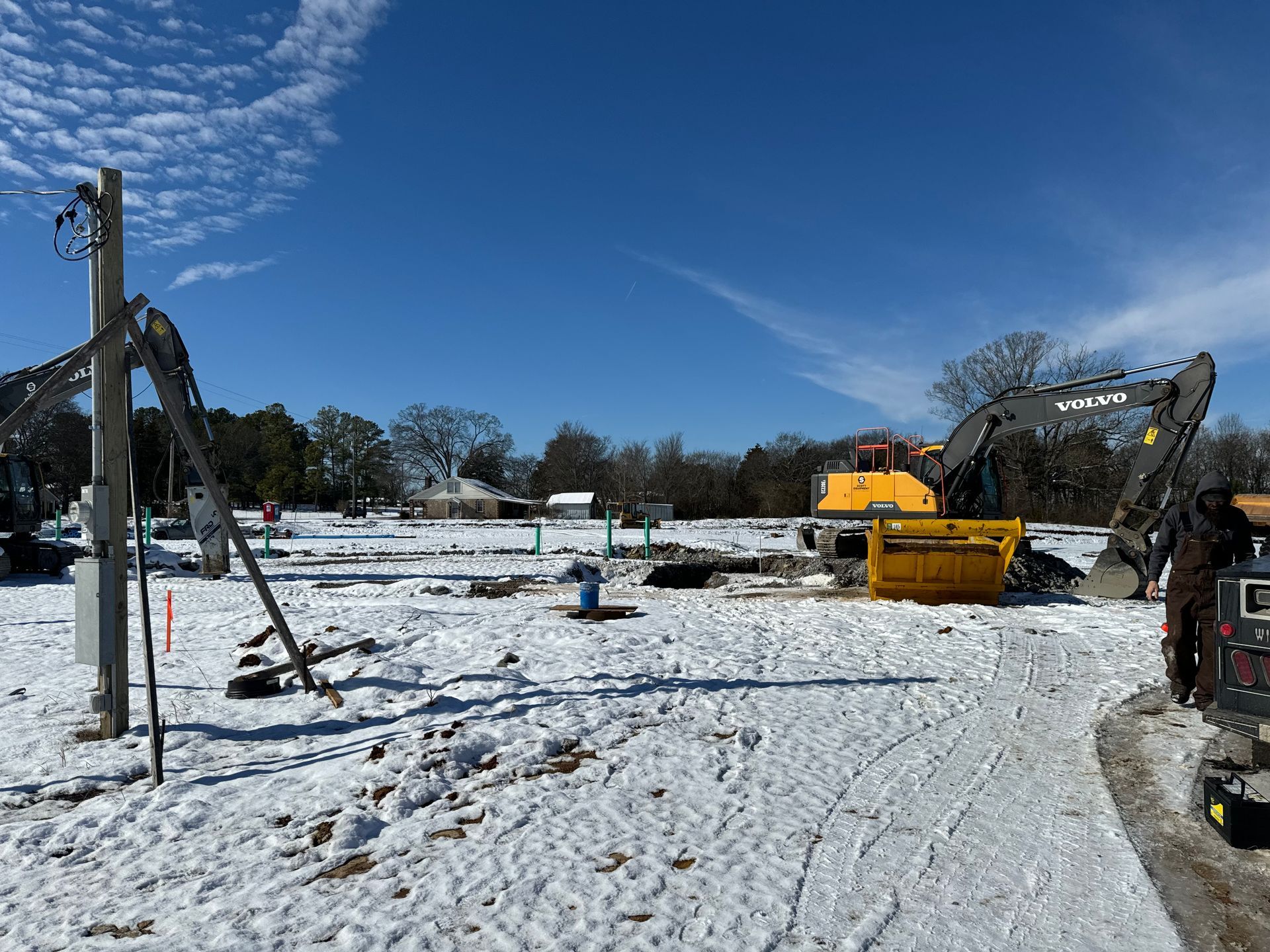 A construction site covered in snow with a volvo excavator in the background.