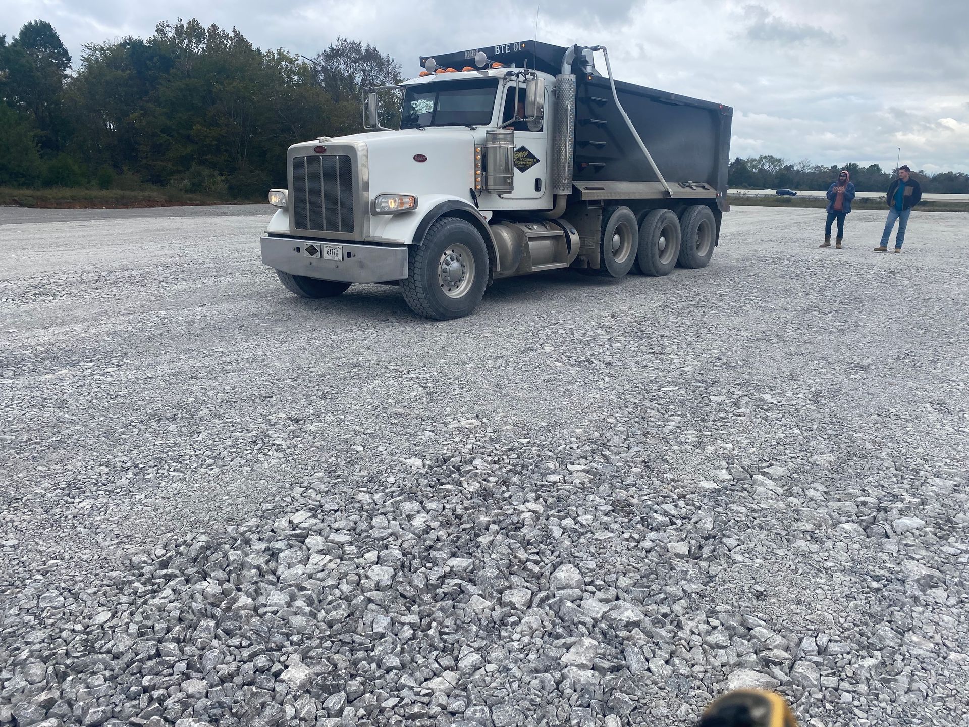 A dump truck is parked in a gravel lot.
