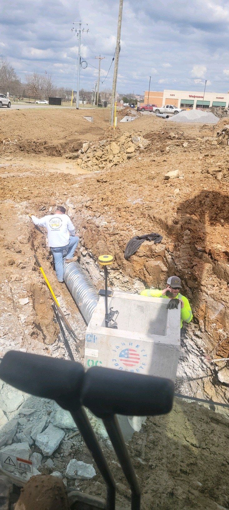 A group of construction workers are working on a pipe in a dirt field.