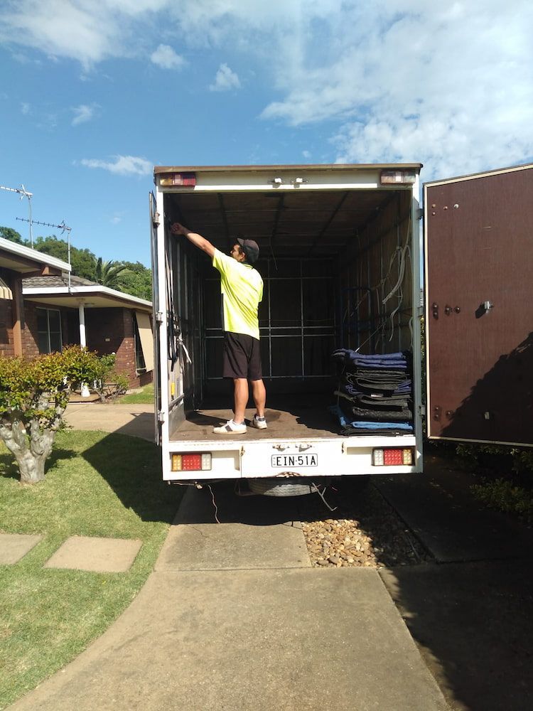 A Man is Standing in the Back of a Moving Truck — TJ Removals and Storage in Wagga Wagga, NSW