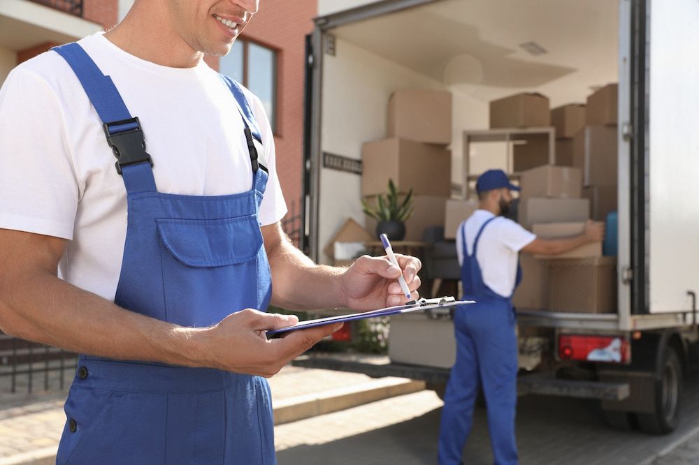 a Man is Writing on a Clipboard in Front of a Moving Truck — TJ Removals and Storage in Albury, NSW