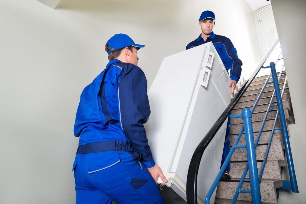 A Man and a Woman Are Carrying a Refrigerator Up a Set of Stairs — TJ Removals and Storage in Wagga Wagga, NSW