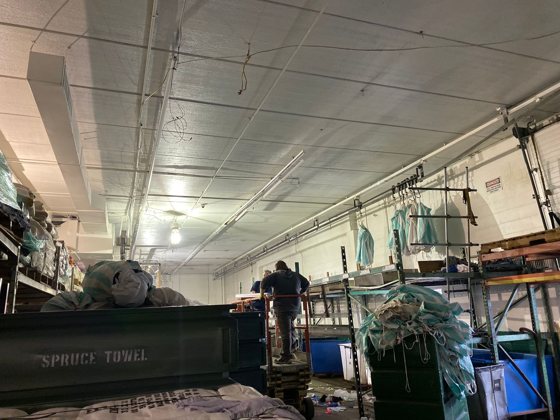 A man is standing on a ladder in a warehouse.