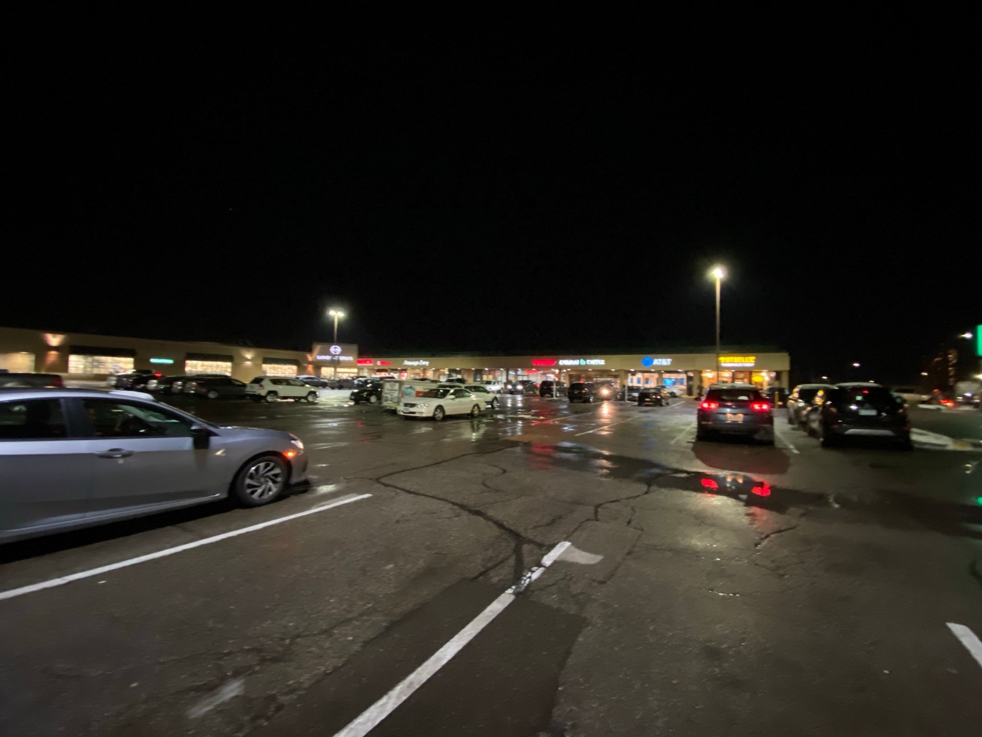 A lot of cars are parked in a parking lot at night.