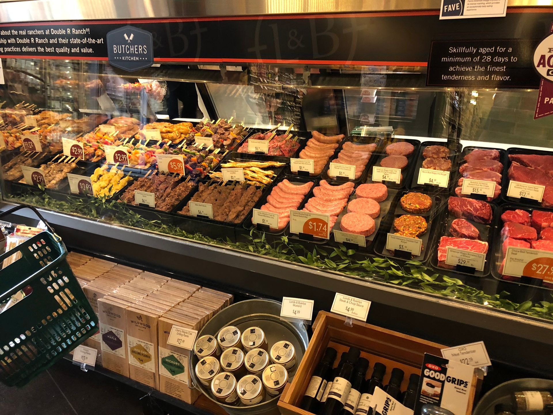 A variety of meats and vegetables are displayed in a butcher shop.