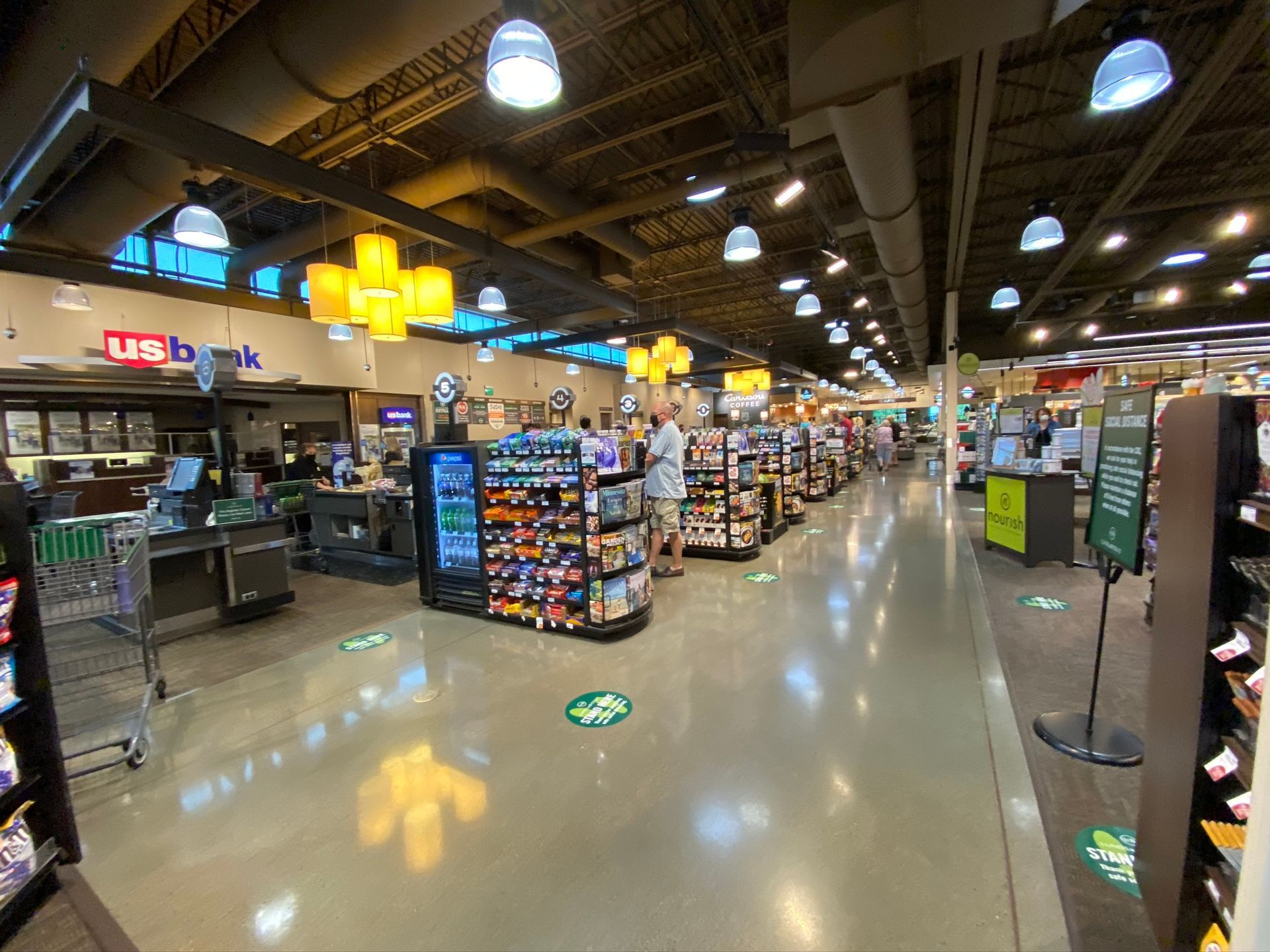 A large grocery store filled with lots of shelves and people.