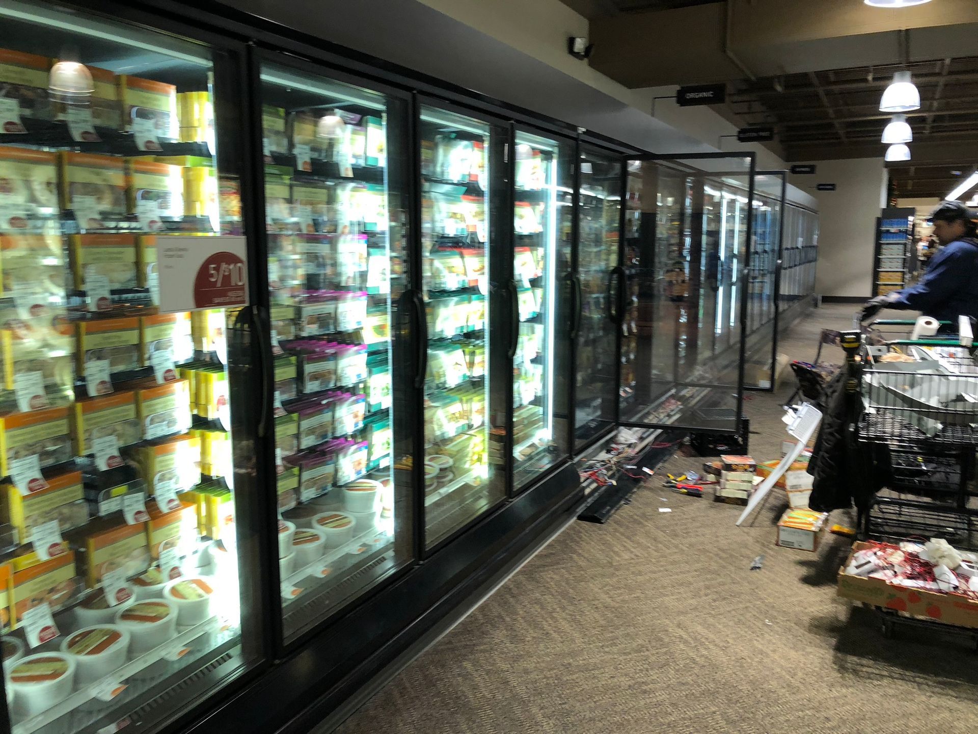 A man is standing in front of a refrigerator in a grocery store.