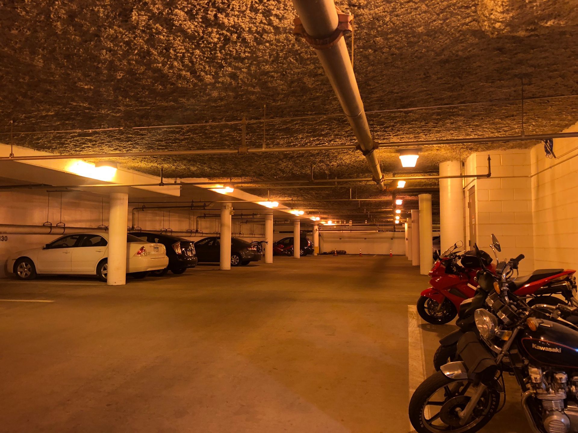 A row of motorcycles are parked in a parking garage