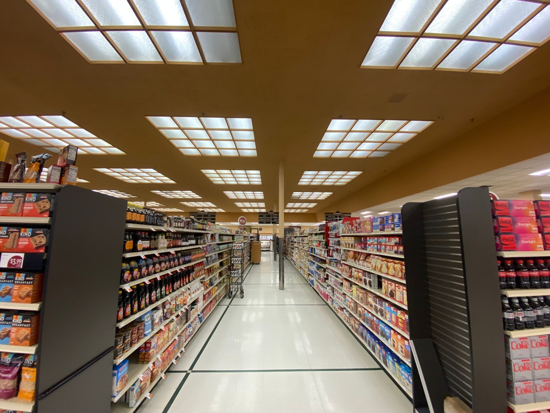 A long aisle of a grocery store with lots of shelves