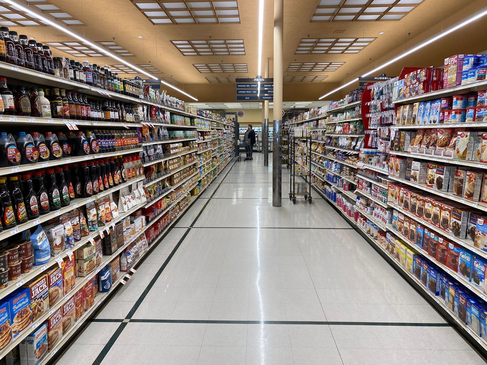 A long aisle of a grocery store filled with lots of products