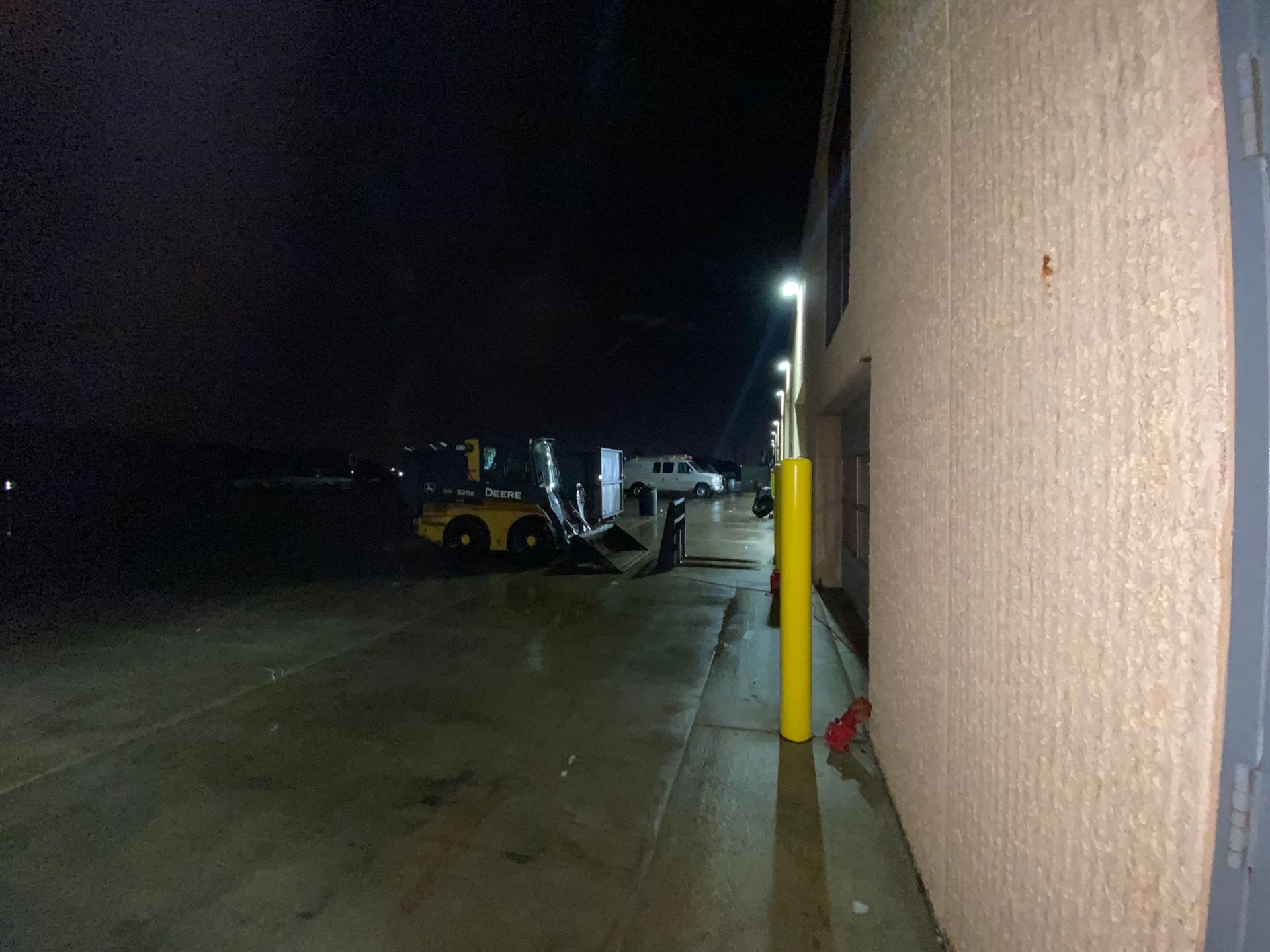 A yellow pole is on the side of a building at night.