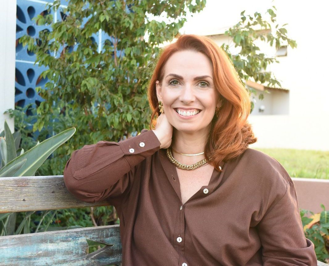 Uma mulher ruiva está sorrindo com a mão no queixo