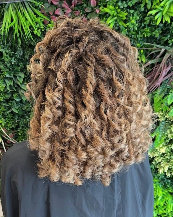 Une petite fille porte un chignon tressé avec une fleur dans les cheveux.