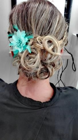 Une femme porte un chignon avec une fleur dans les cheveux.