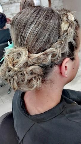 Une femme se fait coiffer dans un salon et a une tresse dans les cheveux.