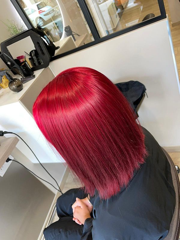 Une femme aux cheveux roux est assise sur une chaise dans un salon.