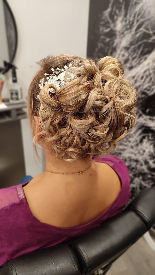 Une femme est assise sur une chaise avec ses cheveux en chignon.