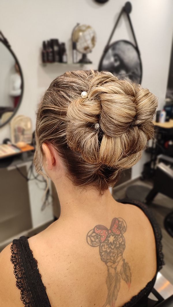 Une femme avec un tatouage dans le dos a les cheveux en chignon.