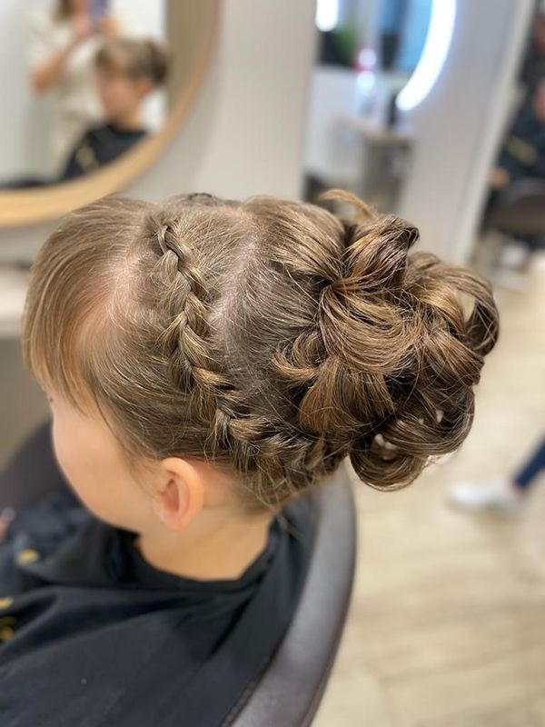 Une petite fille se fait coiffer dans un salon.