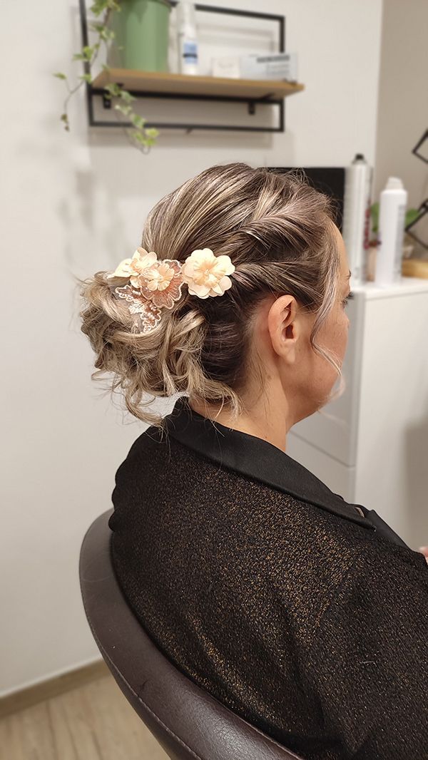 Une femme est assise sur une chaise avec ses cheveux en chignon.